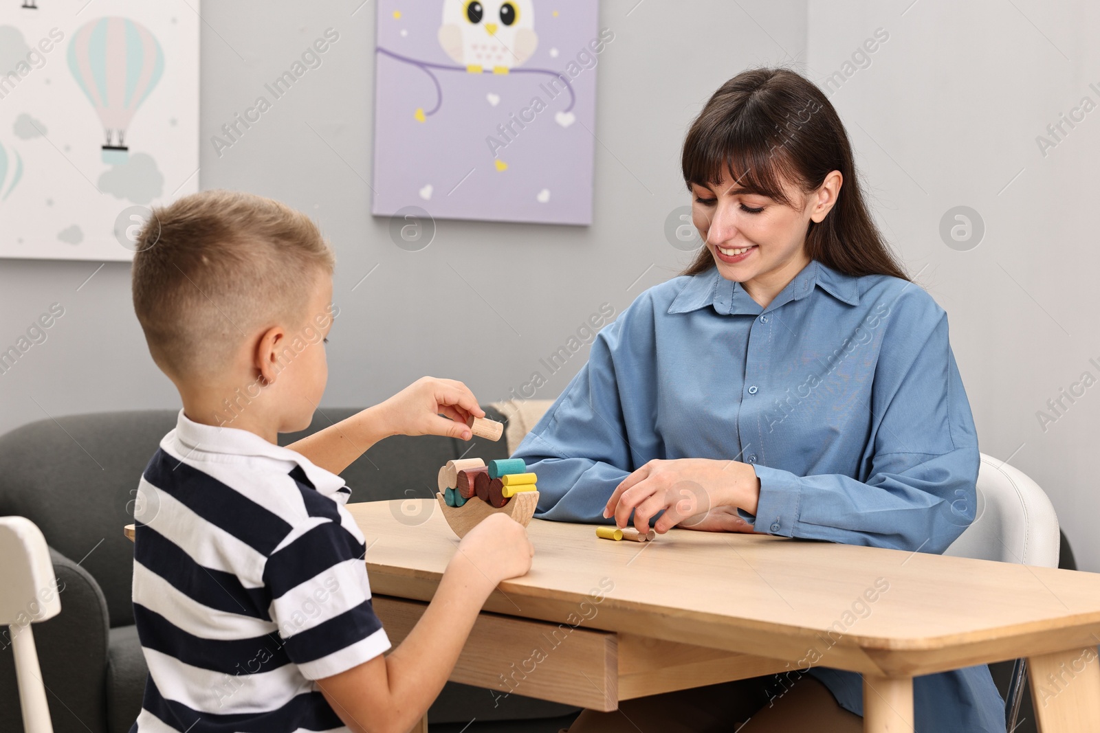 Photo of Autism therapy. Smiling psychologist and little boy playing with educational toy at table in mental health center