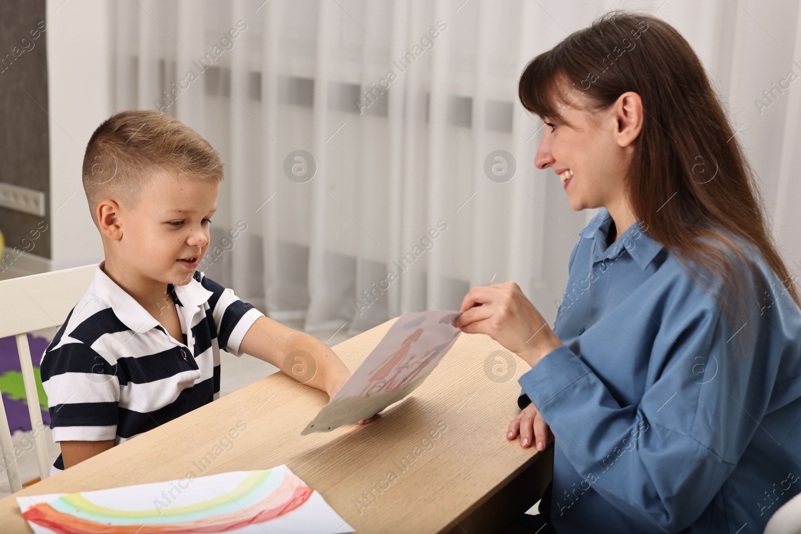 Photo of Smiling psychologist working with little boy in autism treatment center