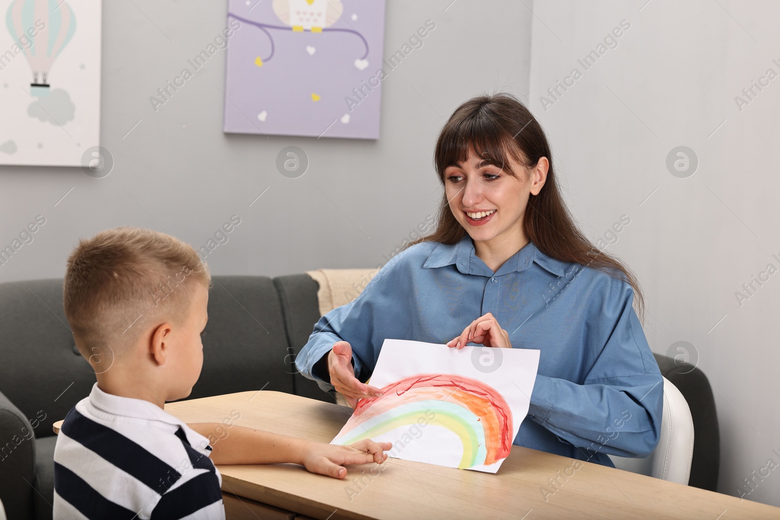 Photo of Smiling psychologist working with little boy in autism treatment center