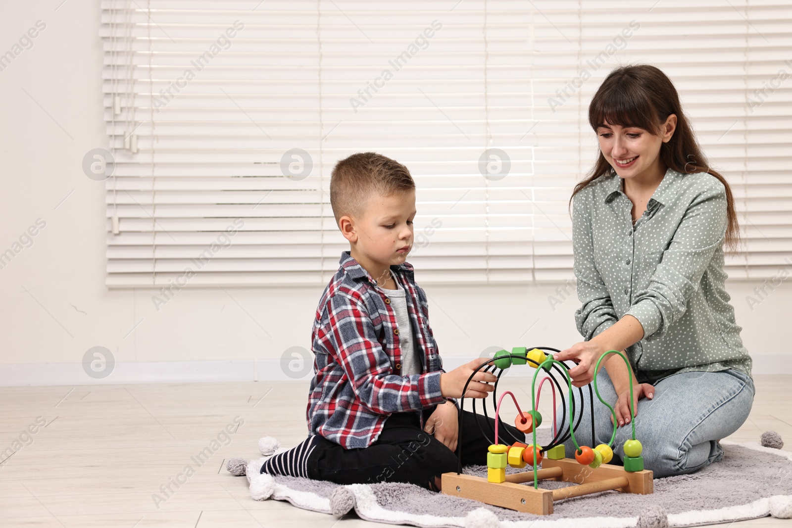 Photo of Autism therapy. Smiling psychologist and little boy playing with educational toy in mental health center, space for text