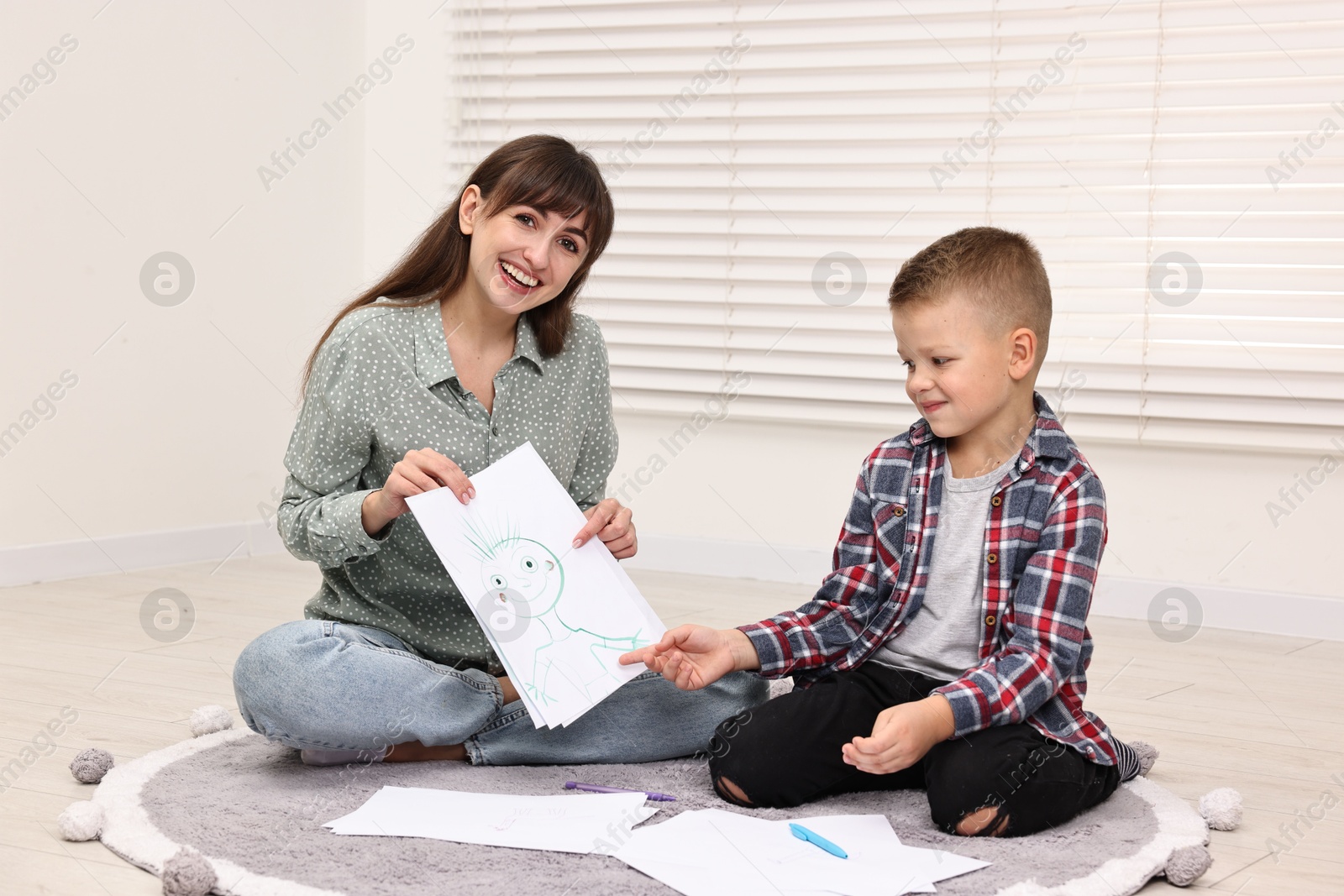 Photo of Smiling psychologist working with little boy in autism treatment center