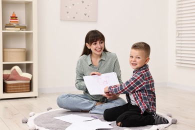 Photo of Smiling psychologist working with little boy in autism treatment center