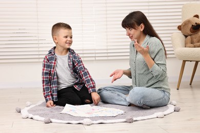 Photo of Speech therapist working with little boy on floor in autism treatment center