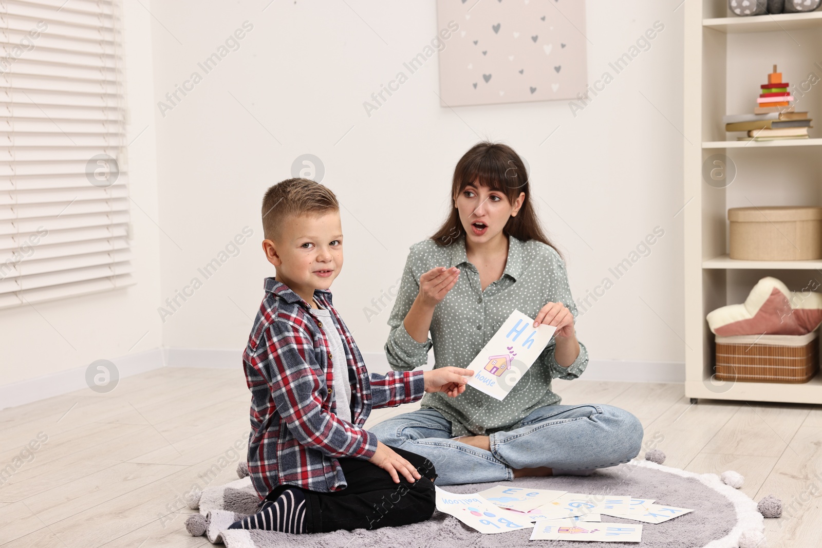 Photo of Speech therapist working with little boy on floor in autism treatment center