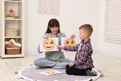 Photo of Autism therapy. Little boy choosing emoticon with smiling psychologist in mental health center