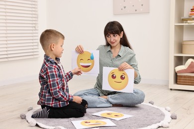 Photo of Autism therapy. Little boy choosing emoticon with psychologist in mental health center