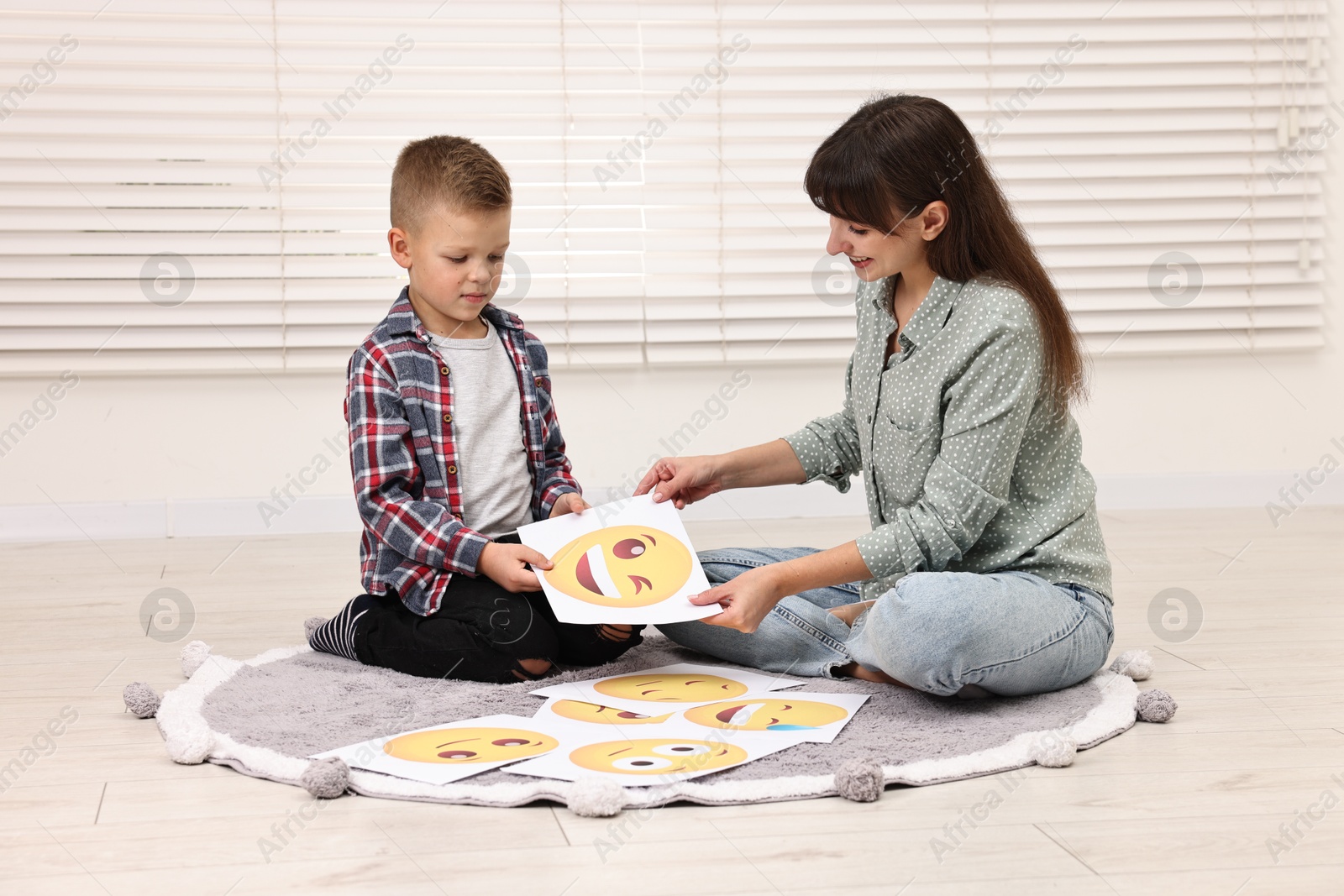 Photo of Autism therapy. Little boy choosing emoticon with smiling psychologist in mental health center