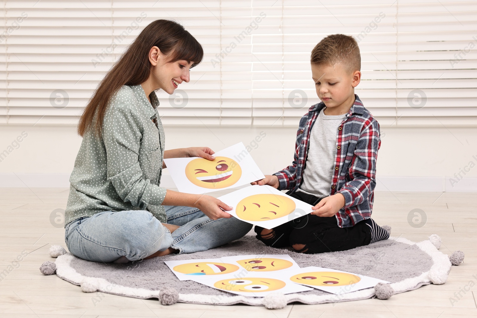 Photo of Autism therapy. Little boy choosing emoticon with smiling psychologist in mental health center