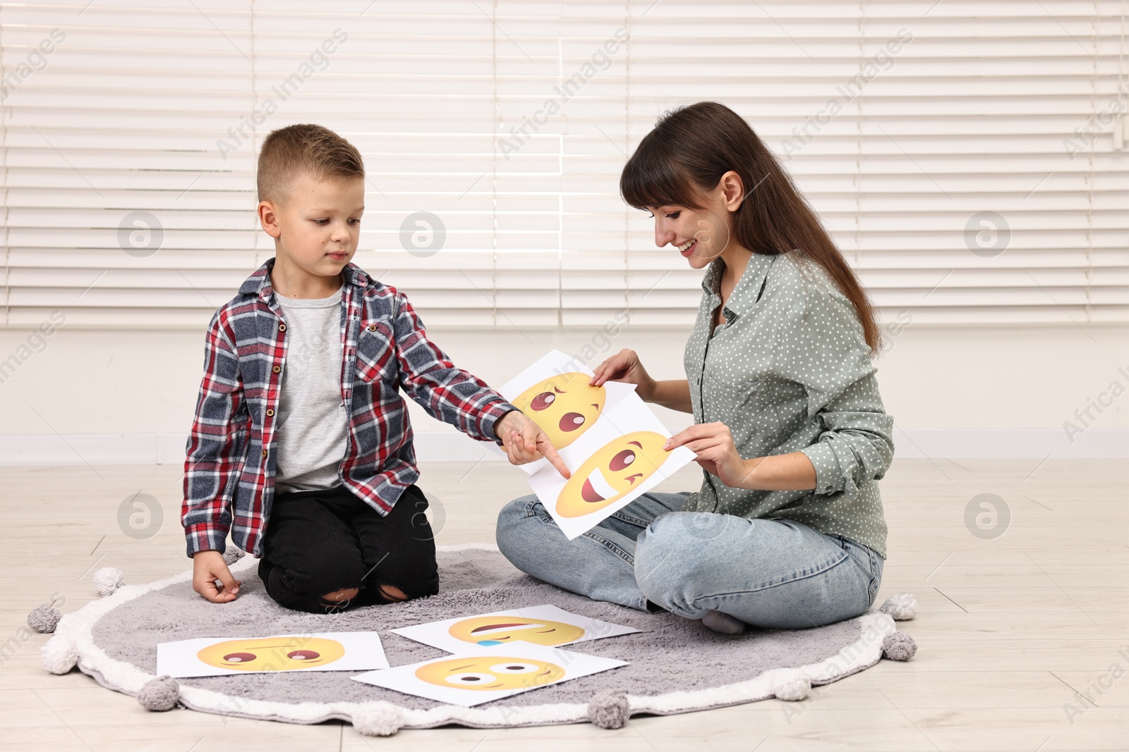 Photo of Autism therapy. Little boy choosing emoticon with smiling psychologist in mental health center