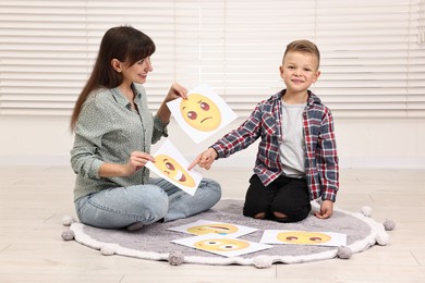 Photo of Autism therapy. Little boy choosing emoticon with smiling psychologist in mental health center