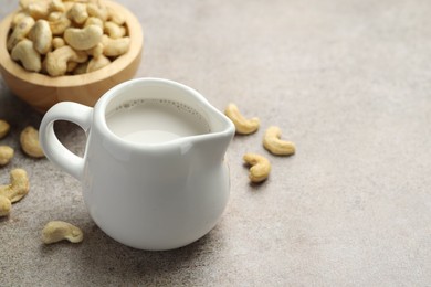 Photo of Fresh cashew milk and nuts on grey textured table, closeup. Space for text