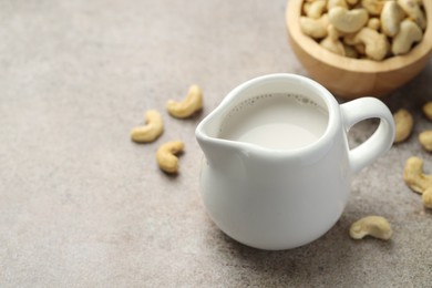 Fresh cashew milk and nuts on grey textured table, closeup. Space for text