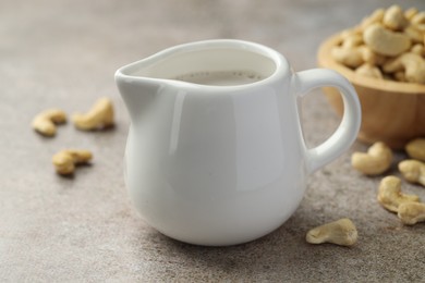 Photo of Fresh cashew milk and nuts on grey textured table, closeup