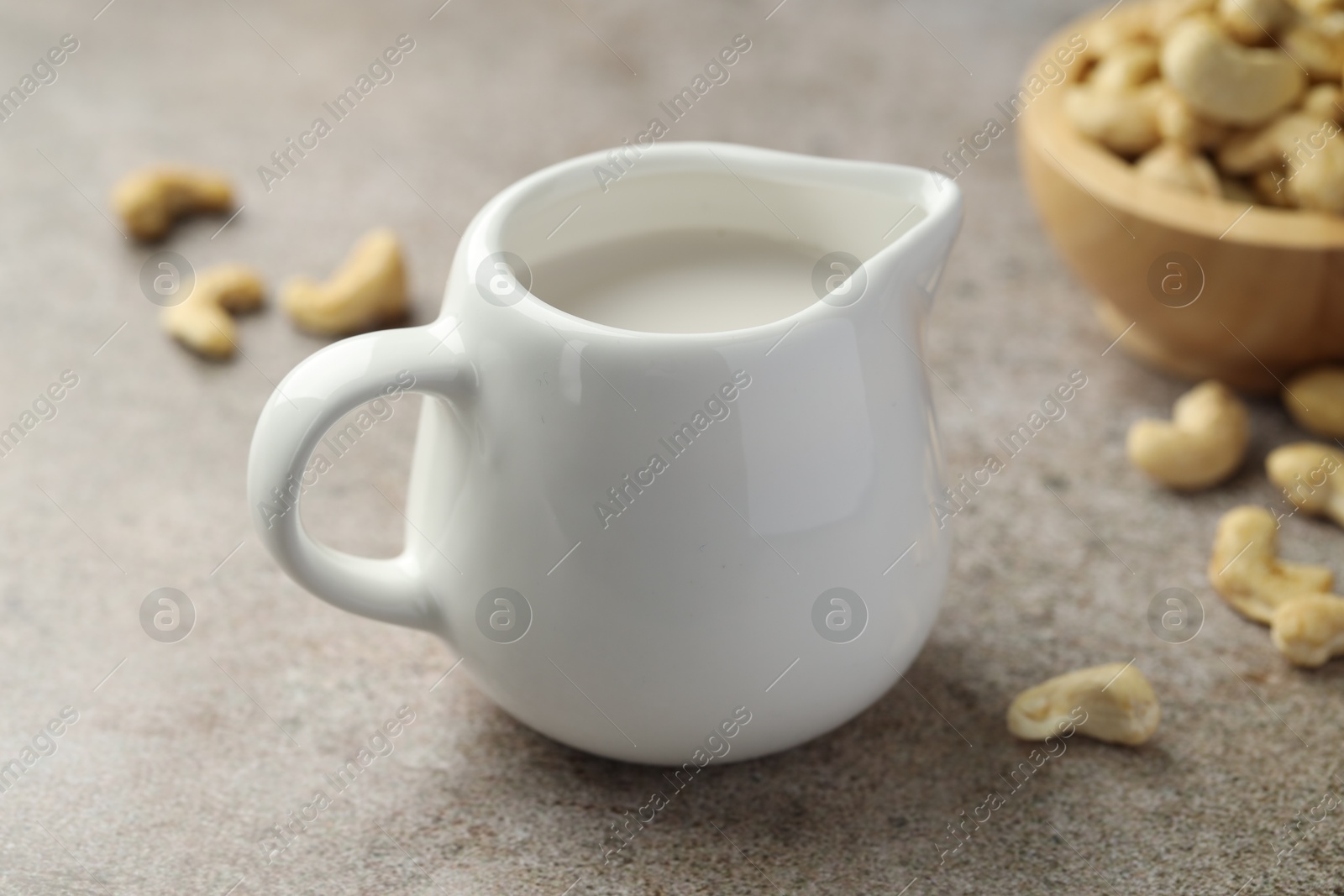 Photo of Fresh cashew milk and nuts on grey textured table, closeup