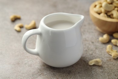 Photo of Fresh cashew milk and nuts on grey textured table, closeup