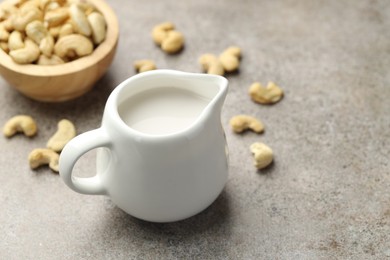 Photo of Fresh cashew milk and nuts on grey textured table, closeup