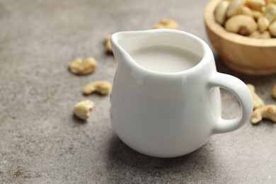 Photo of Fresh cashew milk and nuts on grey textured table, closeup