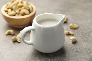 Photo of Fresh cashew milk and nuts on grey textured table, closeup