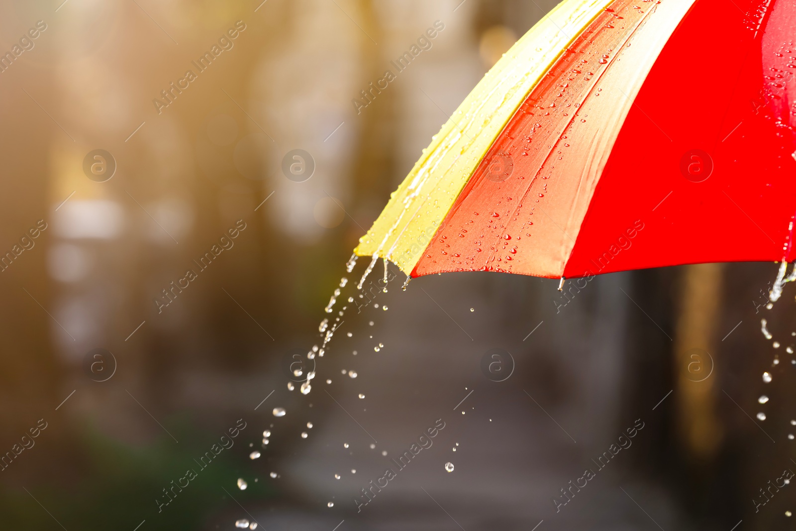 Photo of Open bright umbrella under pouring rain outdoors, closeup