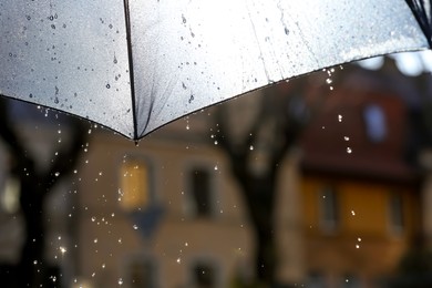 Photo of Open umbrella under pouring rain outdoors, closeup