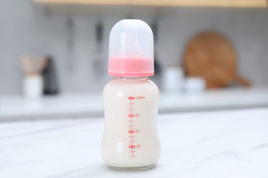 Photo of Feeding bottle with baby formula on white table indoors