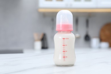 Photo of Feeding bottle with baby formula on white table indoors