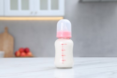 Photo of Feeding bottle with baby formula on white table indoors