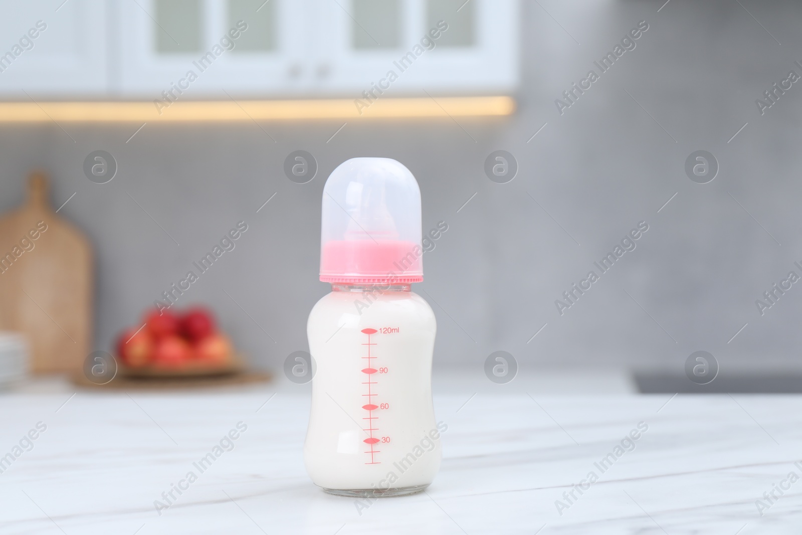 Photo of Feeding bottle with baby formula on white table indoors