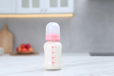 Photo of Feeding bottle with baby formula on white table indoors