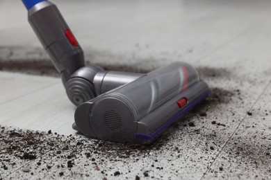 Photo of Cleaning floor with cordless vacuum cleaner indoors, closeup