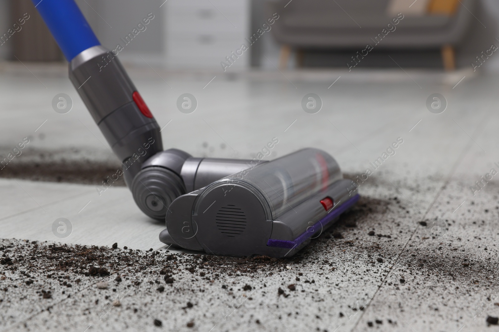 Photo of Cleaning floor with cordless vacuum cleaner indoors, closeup