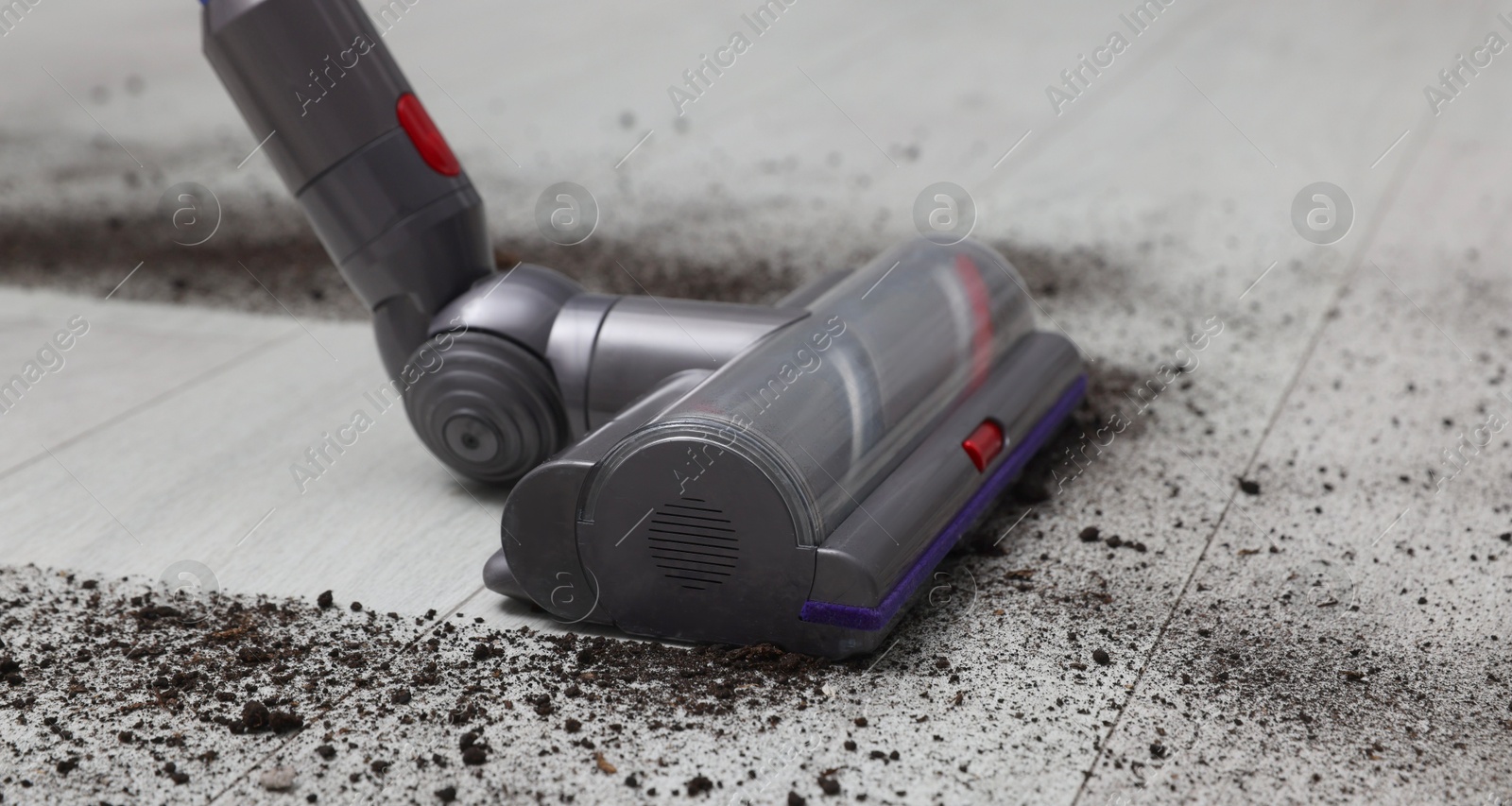 Photo of Cleaning floor with cordless vacuum cleaner indoors, closeup