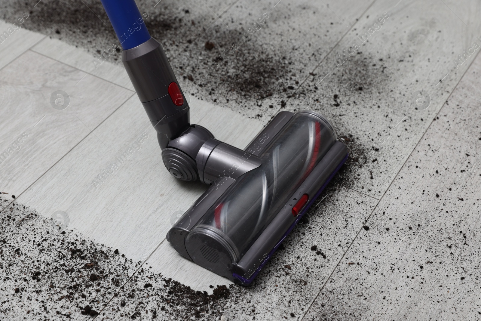 Photo of Cleaning floor with cordless vacuum cleaner indoors, closeup