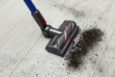 Photo of Cleaning floor with cordless vacuum cleaner indoors, closeup