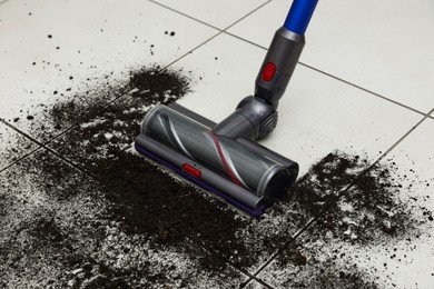 Photo of Cleaning floor with cordless vacuum cleaner indoors, closeup