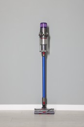 Photo of One cordless vacuum cleaner near grey wall indoors