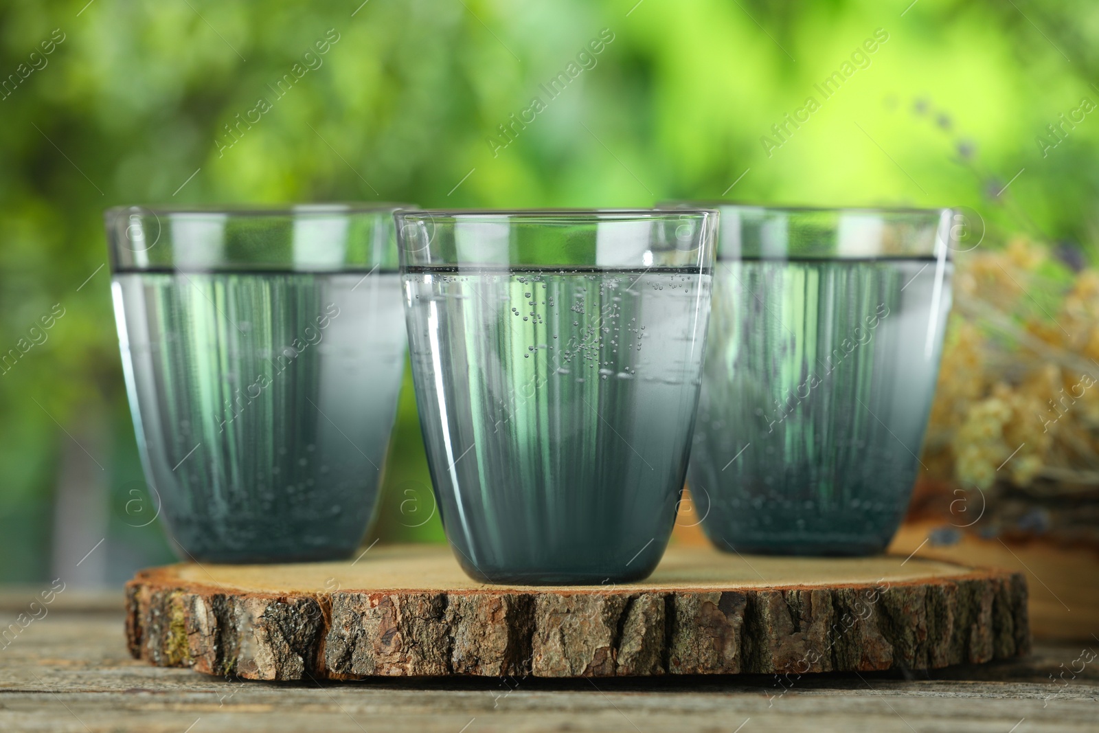 Photo of Soda water in glasses on wooden table outdoors