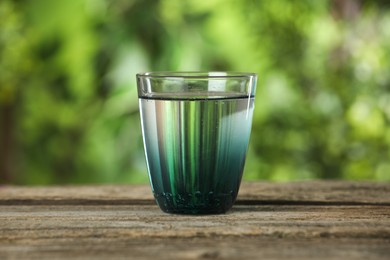 Photo of Soda water in glass on wooden table outdoors