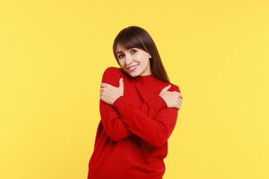 Photo of Young woman hugging himself on yellow background