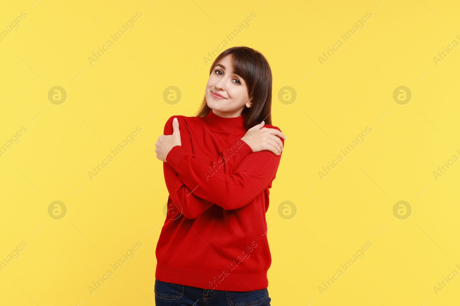 Photo of Young woman hugging himself on yellow background