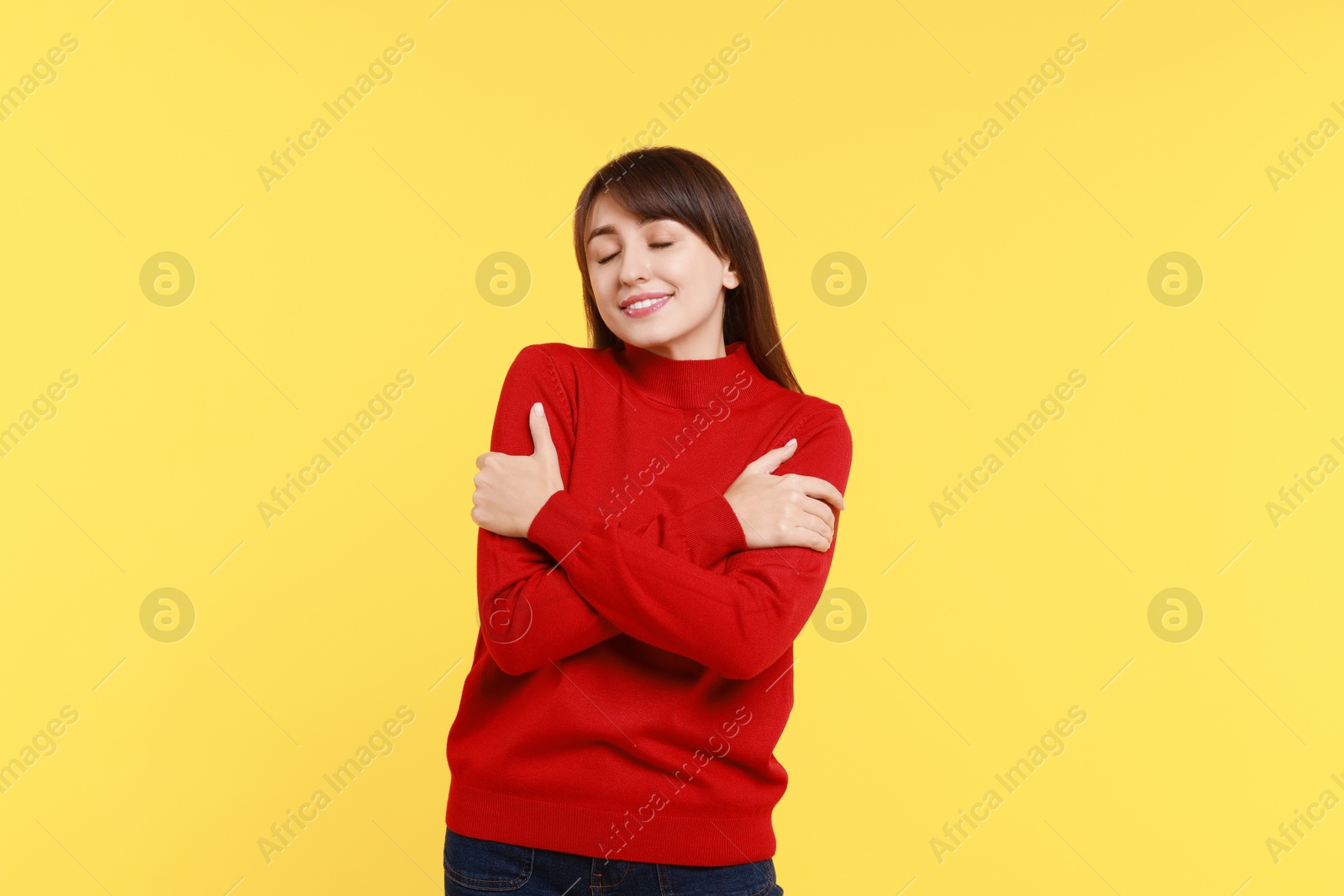 Photo of Young woman hugging himself on yellow background