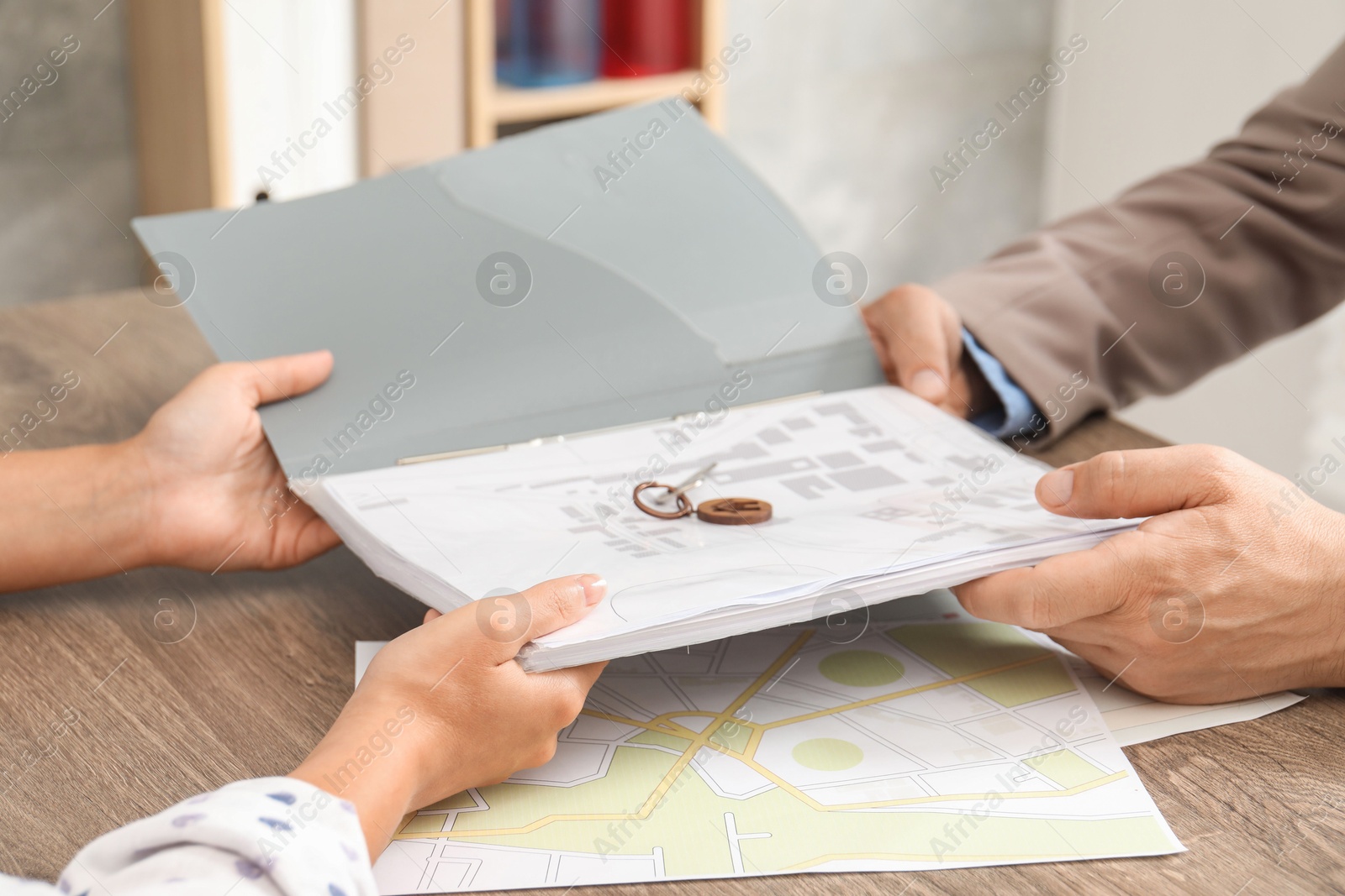 Photo of Real estate agent working with client at wooden table, closeup