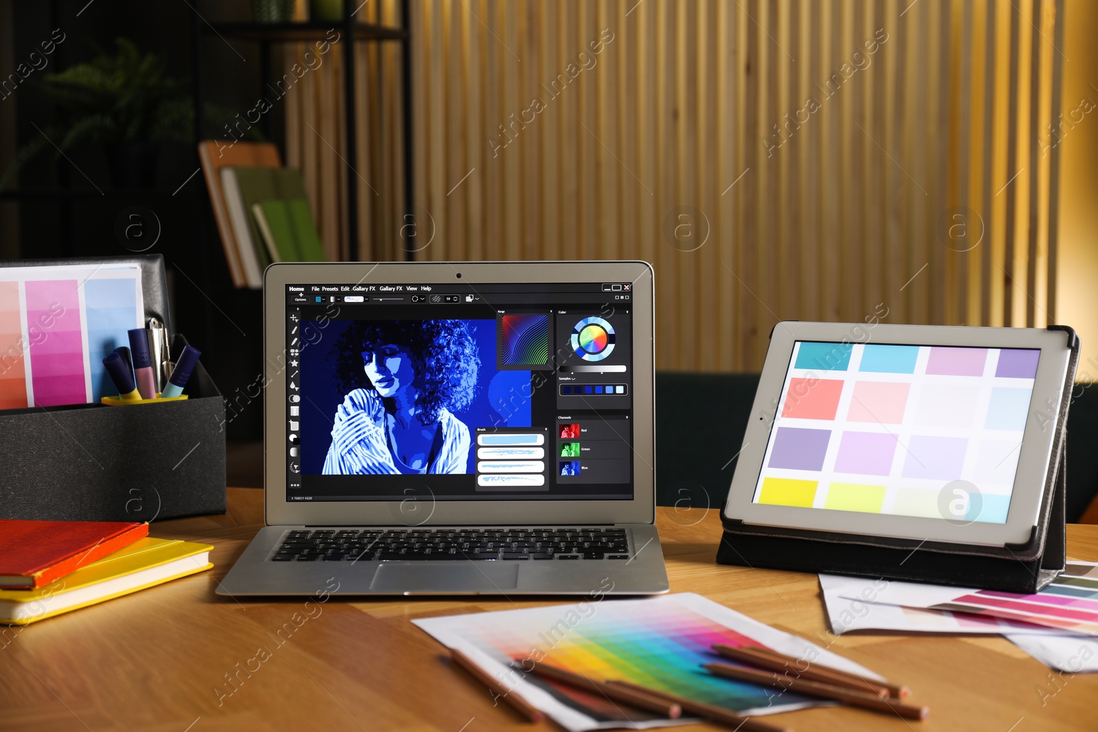 Photo of Designer's workplace with laptop, tablet, stationery and palettes on wooden table indoors