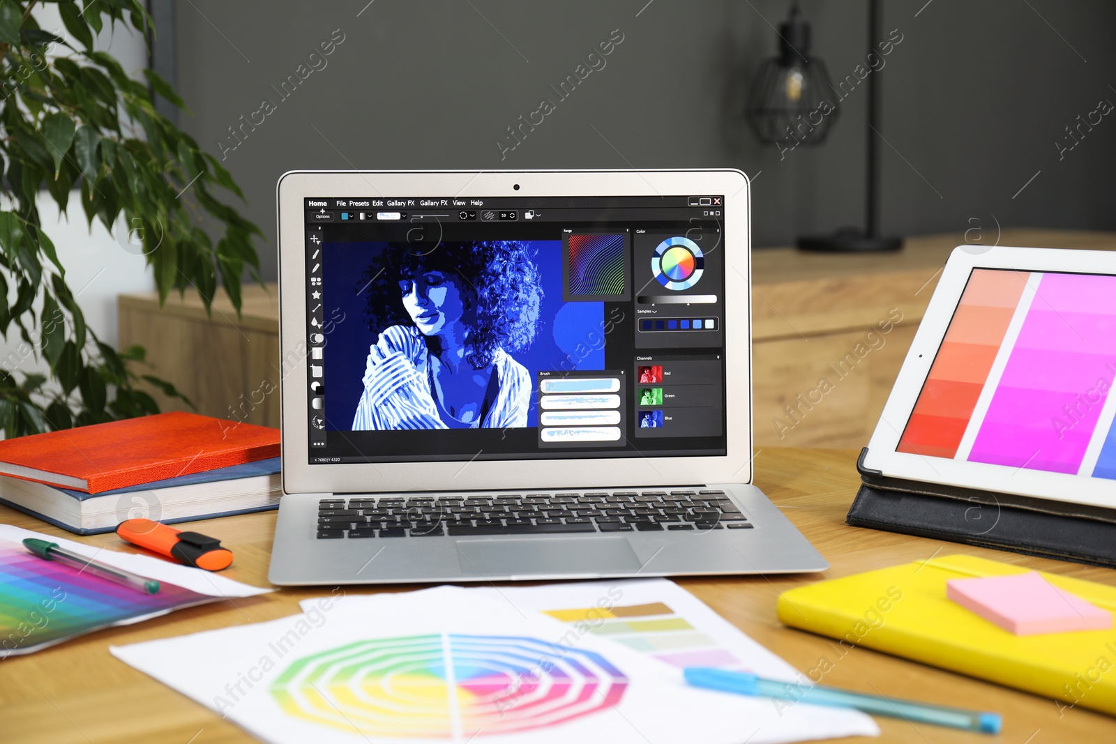 Photo of Designer's workplace with laptop, tablet, stationery and palettes on wooden table indoors