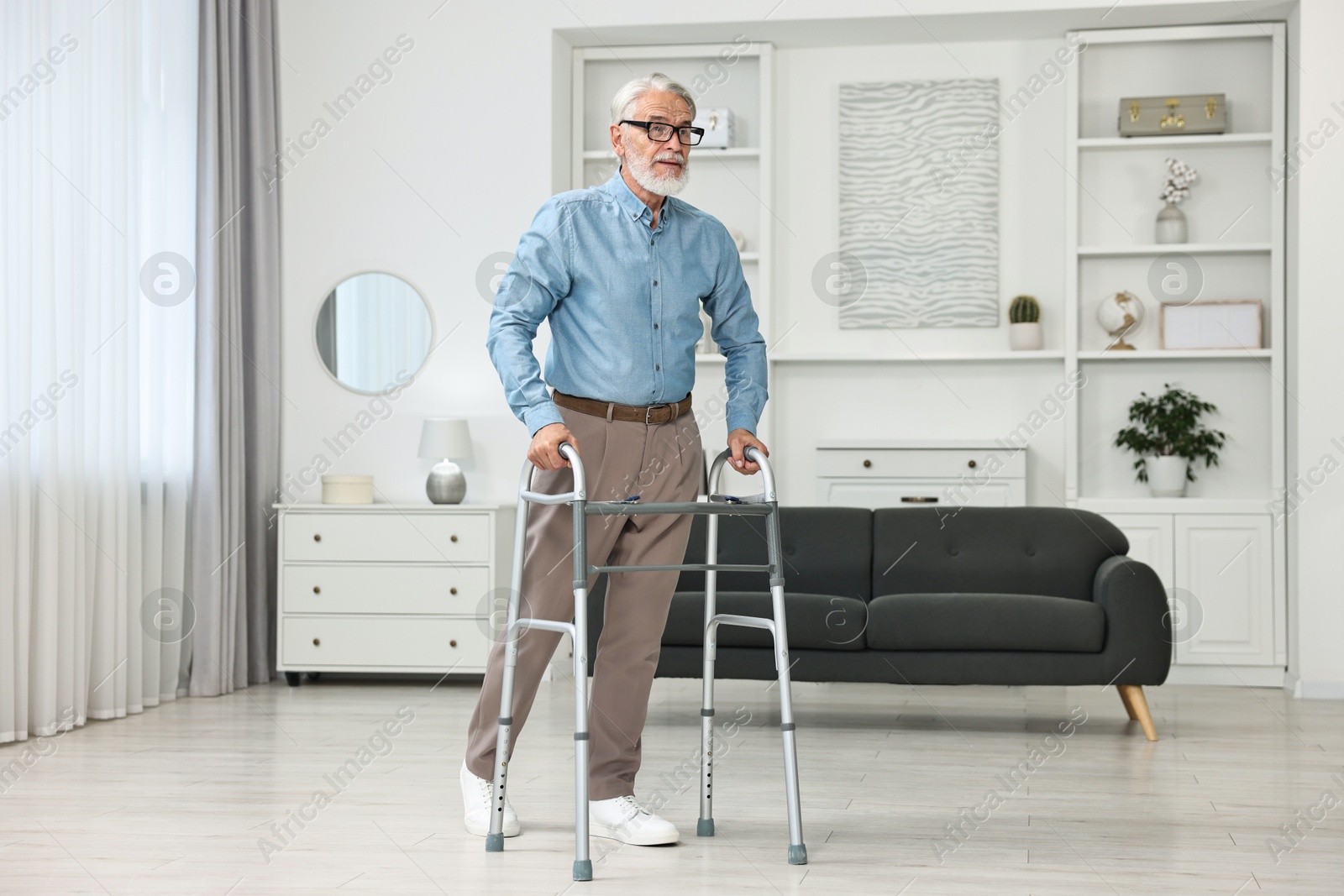 Photo of Senior man using walking frame at home