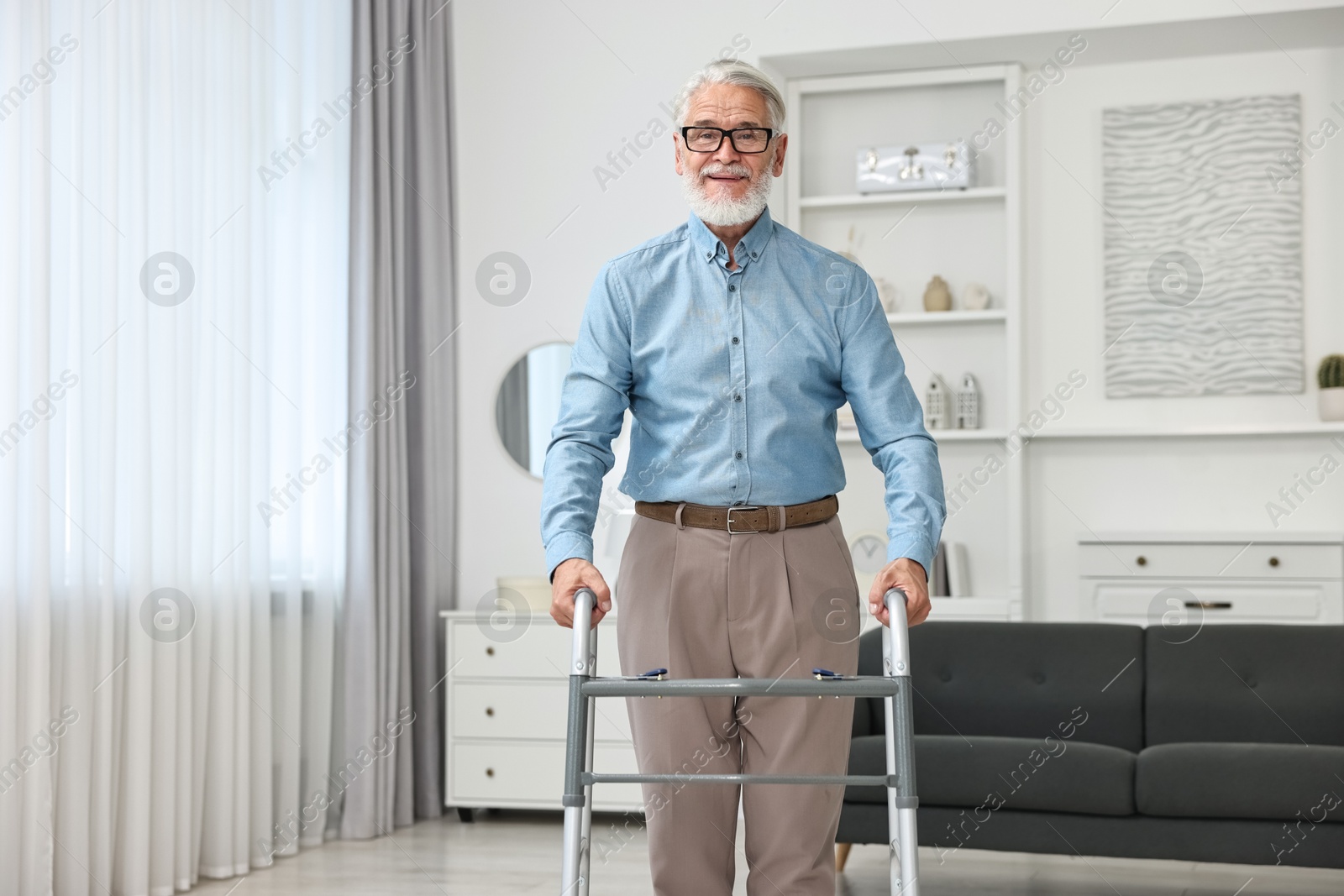 Photo of Senior man using walking frame at home