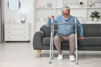 Photo of Senior man with walking frame on sofa at home