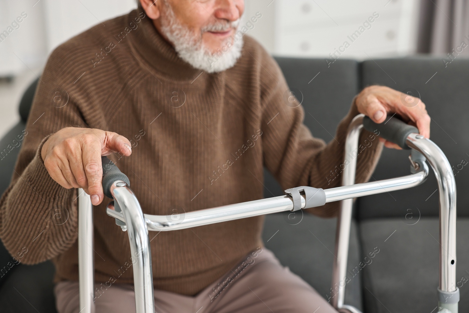 Photo of Senior man with walking frame on sofa at home, closeup