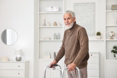 Photo of Senior man using walking frame at home