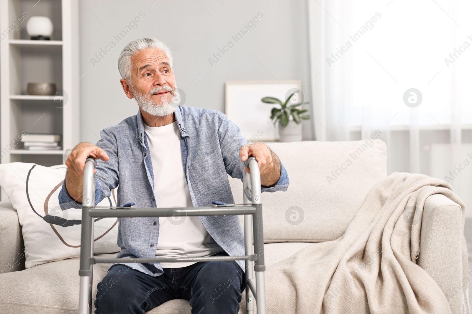 Photo of Senior man with walking frame on sofa at home